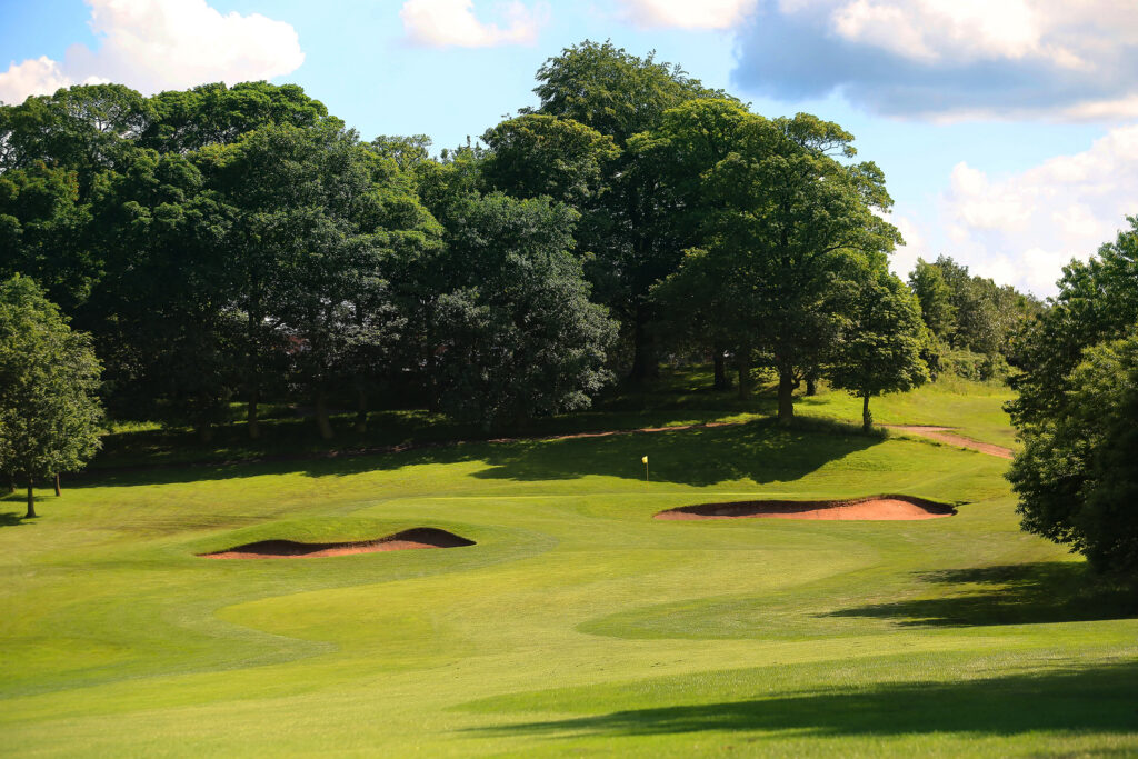 Hole with yellow flag and bunkers at Oulton Hall Golf Club with trees around