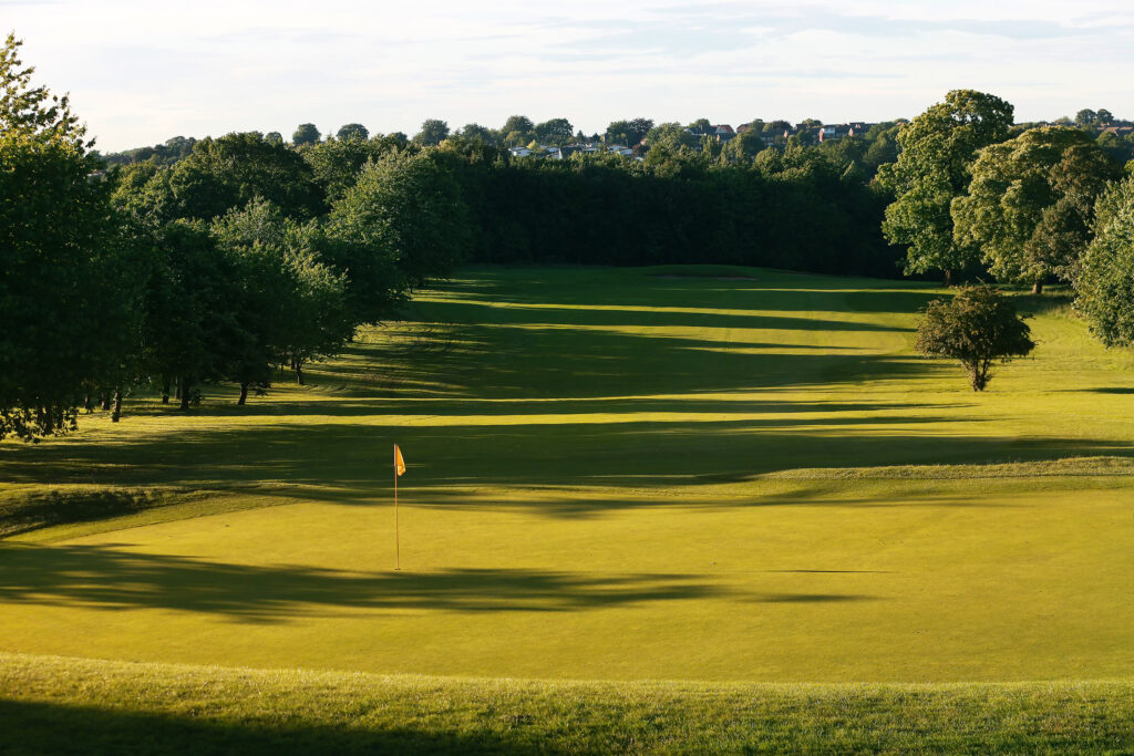 Hole with yellow flag at Oulton Hall Golf Club with trees around