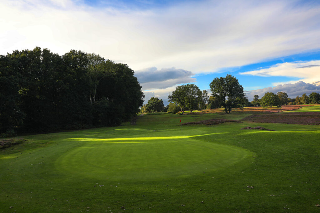 Hole with red flag at Piltdown Golf Club with trees around