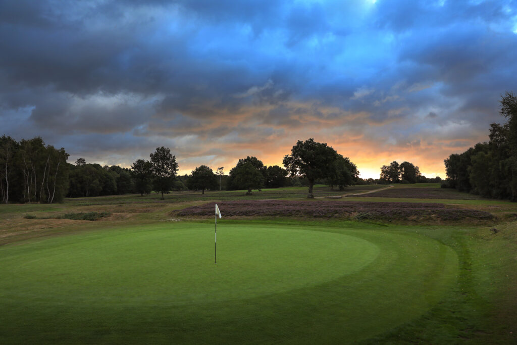 Hole with trees around at Piltdown Golf Club at sunset