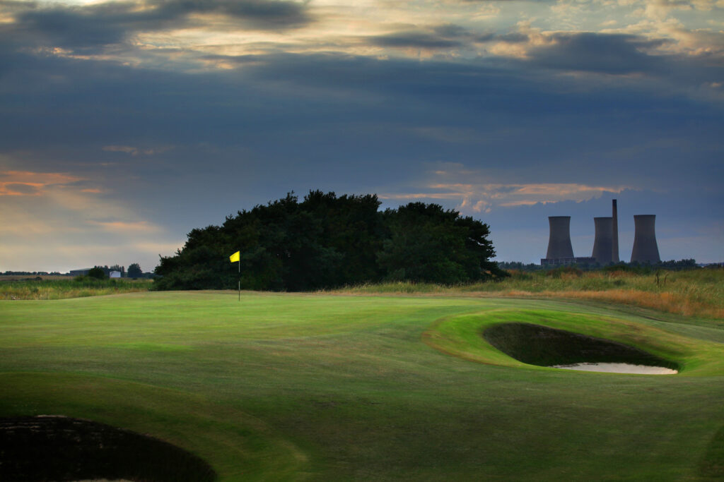 Hole with yellow flag with bunker and trees in background at Prince's Golf Club