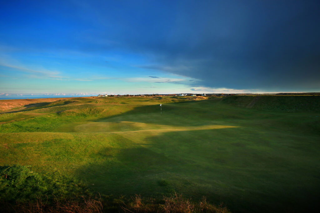 Hole with white flag with mounds around at Royal Cinque Ports Golf Club