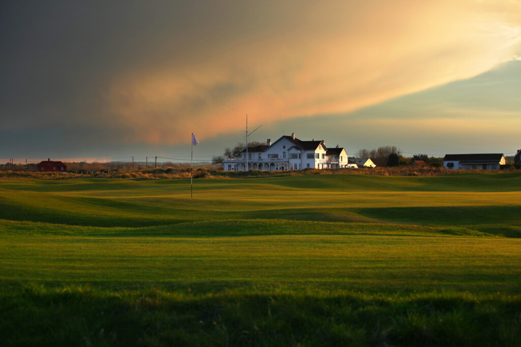 Hole with white flag with clubhouse in background at Royal Cinque Ports Golf Club