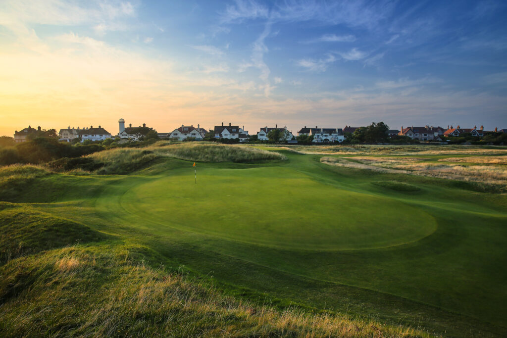 Hole with yellow flag with buildings in distance at Royal Liverpool Golf Club