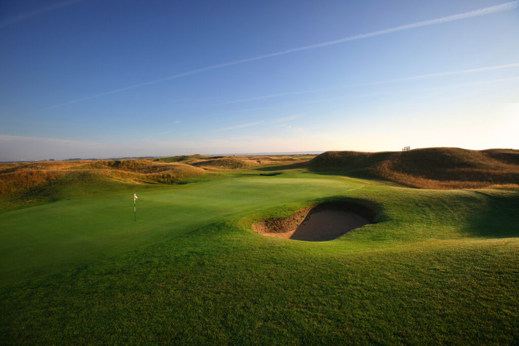 Hole with white flag and bunker with mounds around at Royal St George's Golf Club