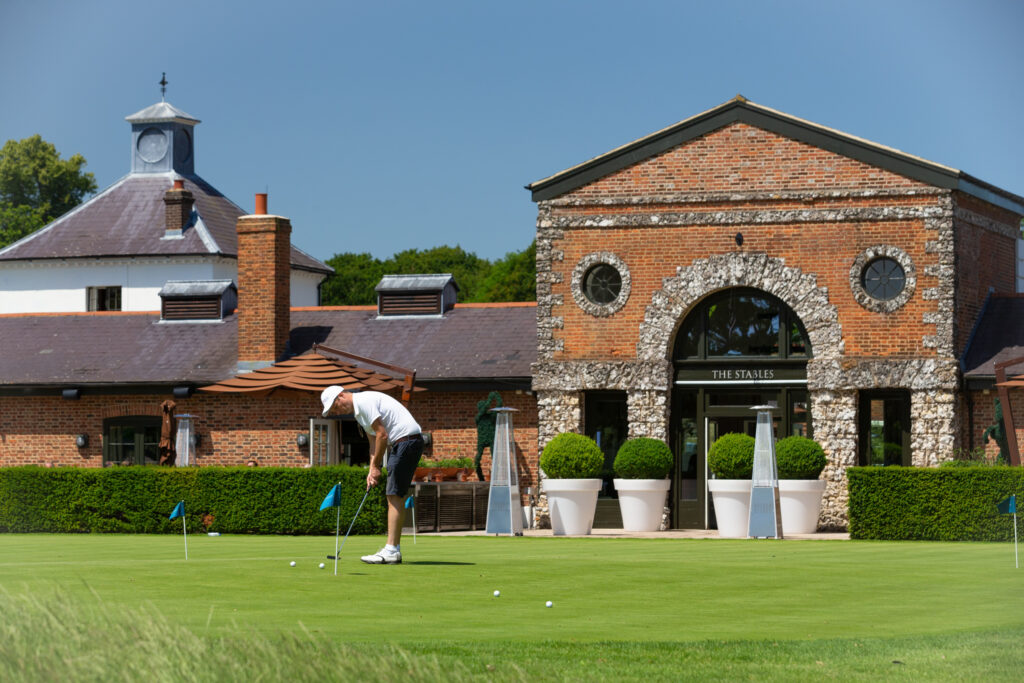 Person using the practice facilities at The Grove - Championship with building in background