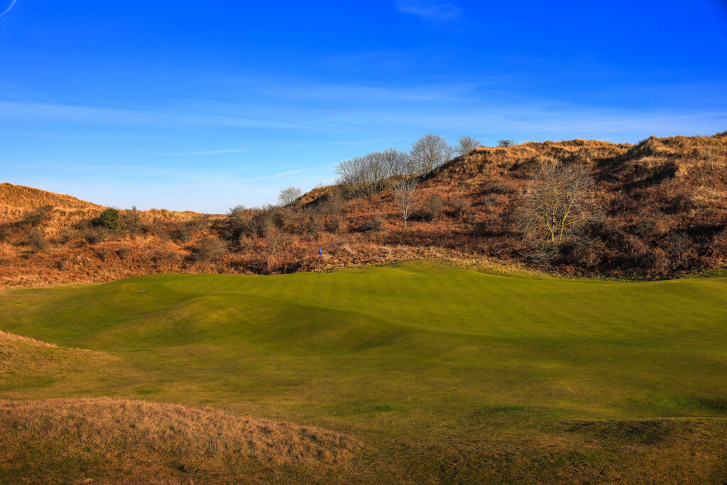 Hole with blue flag at The Island Golf Club with mounds around