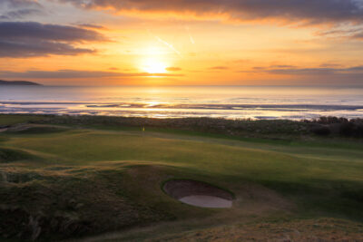 Hole with bunker at The Island Golf Club with ocean in background at sunset