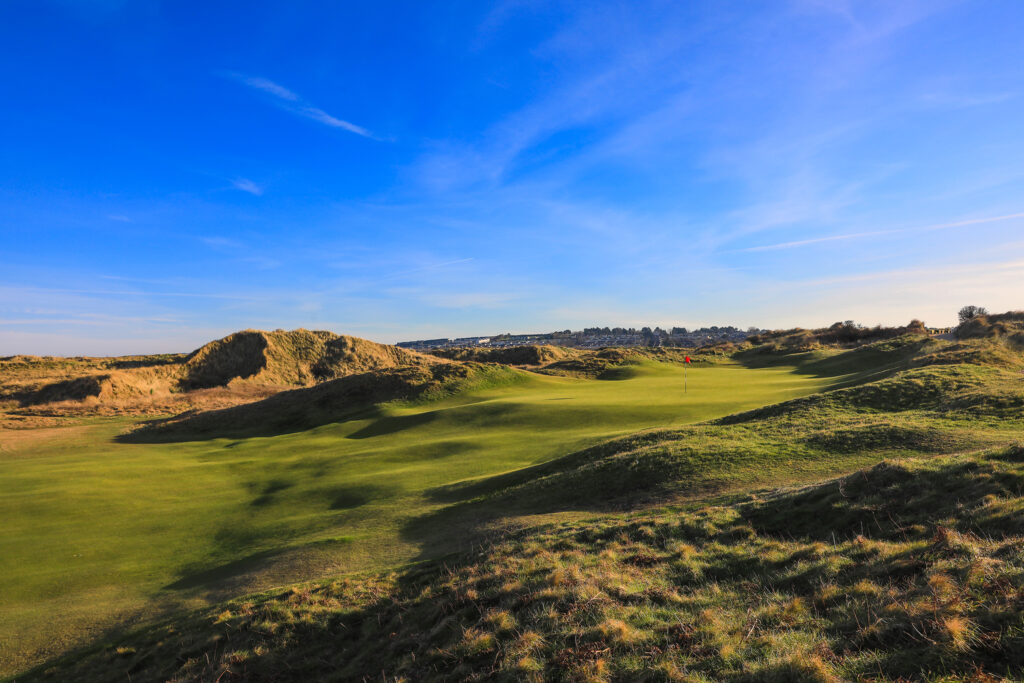 Hole with red flag at The Island Golf Club with mounds around