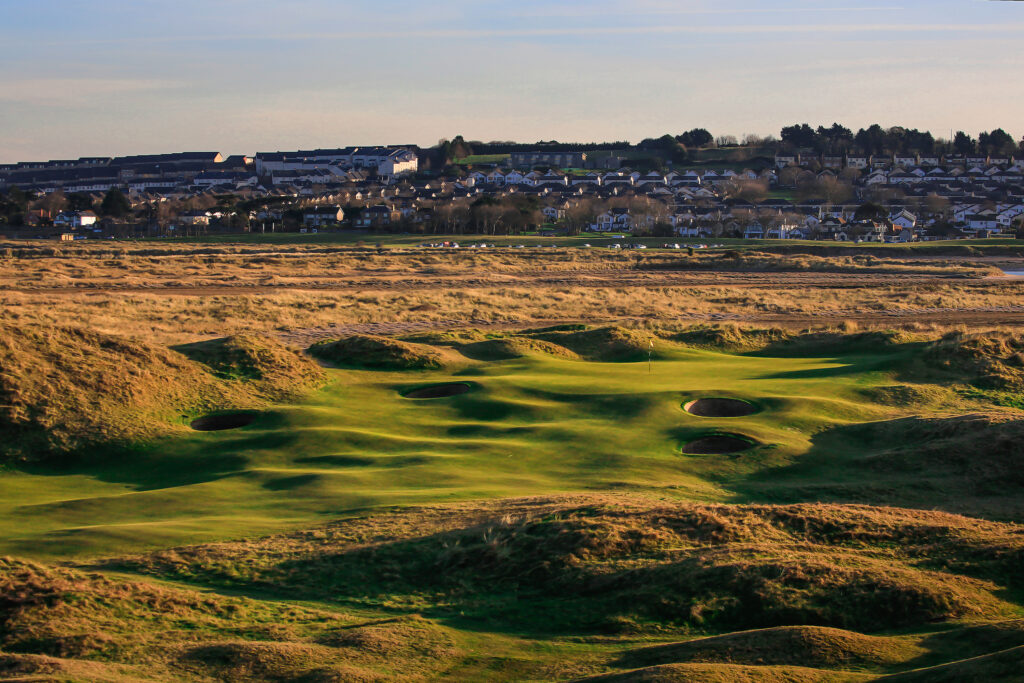 Hole with bunkers at The Island Golf Club with buildings in distance