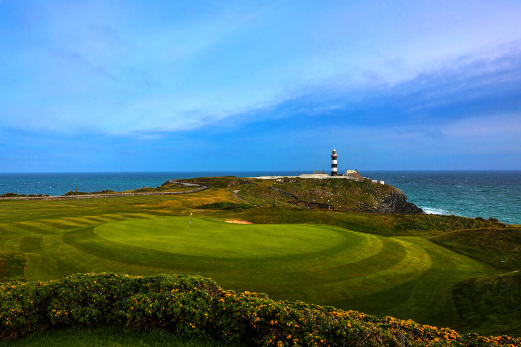 Hole with yellow flag at Old Head Links with lighthouse in distance