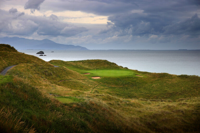 View of hole with yellow flag and bunkers at Tralee Golf Club with ocean view