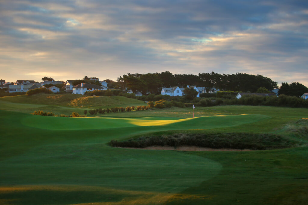 Hole with white flag with houses in background at Championship Course at Trevose Golf & Country Club