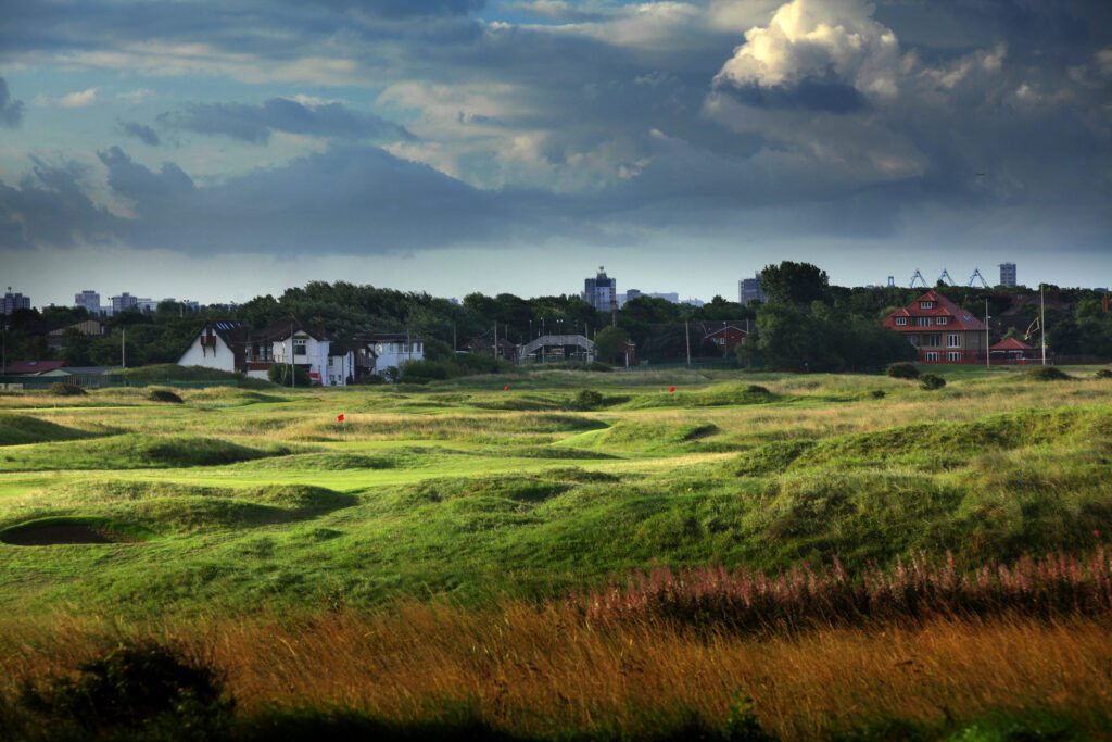 Fairway with mounds and bunkers at West Lancashire Golf Club with buildings in background