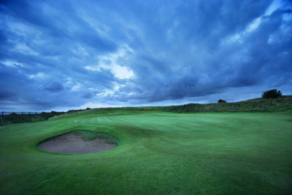 Hole with red flag at West Lancashire Golf Club with bunker