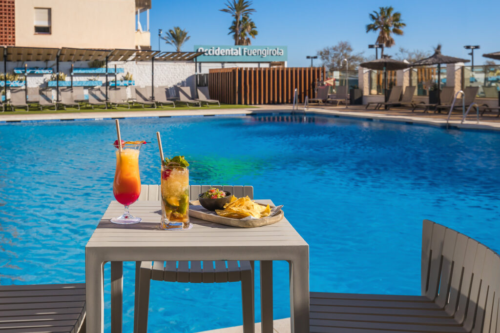 Table and chairs with food and drink by outdoor pool at Occidental Fuengirola