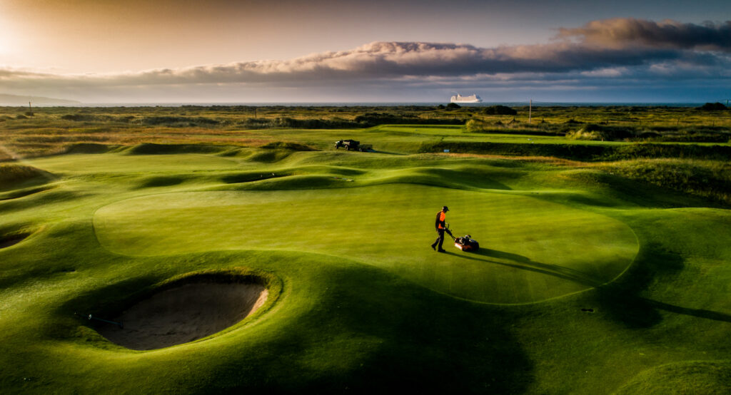 Person mowing a green at Royal Dublin Golf Club