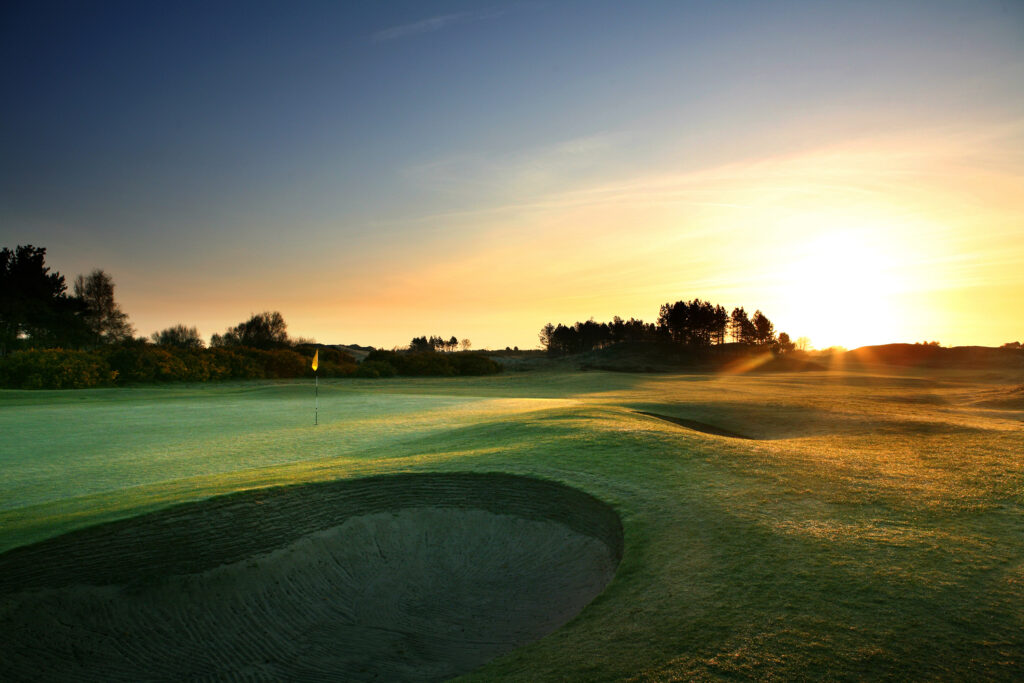 Hole with yellow flag and bunkers with trees around at Southport & Ainsdale