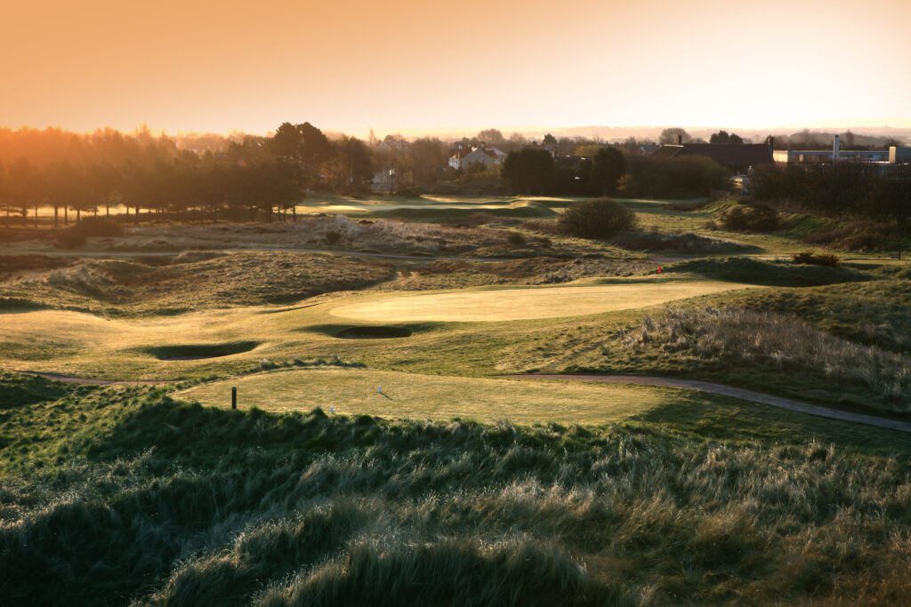 Tee box overlooking fairway and hole with red flag with trees in background at Southport & Ainsdale