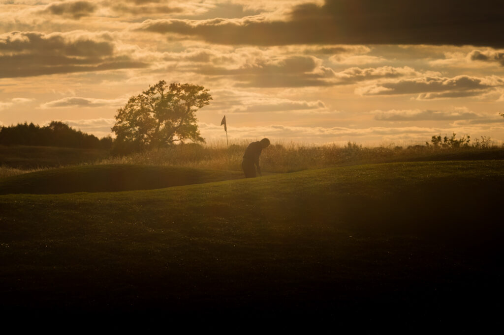 Person playing golf at The Oxfordshire at sunset