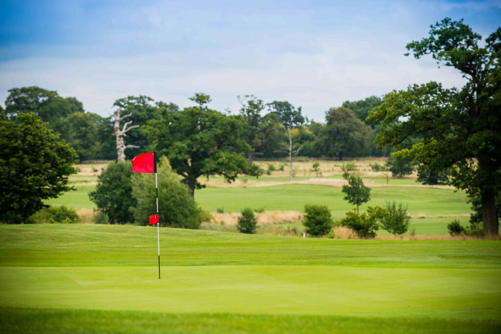 Hole with red flag at Whittlebury Park Golf Course with trees around