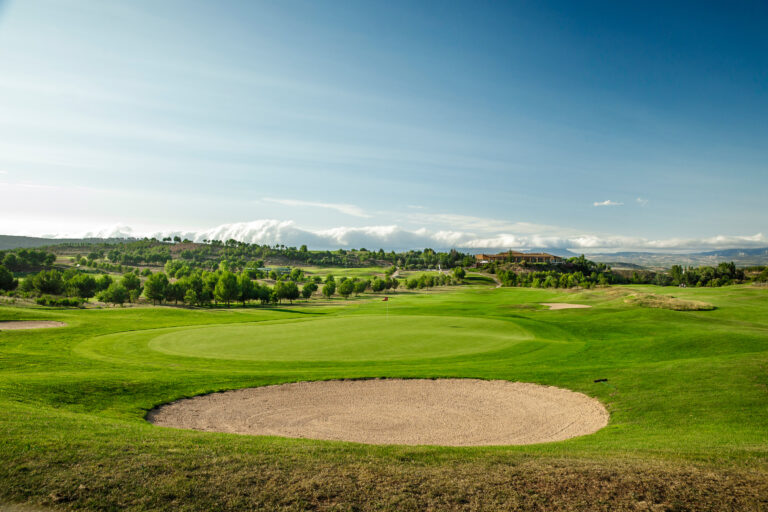 Hole with bunker at Campo de Golf Logrono with trees in distance