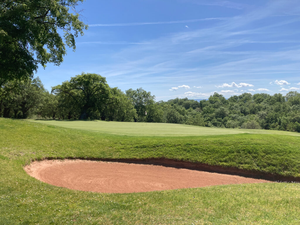 Hole with bunker at Rioja Alta Golf Club with trees around