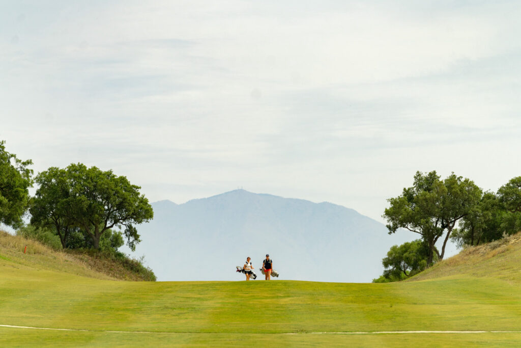 People walking on fairway with golf bags at San Roque Golf & Resort