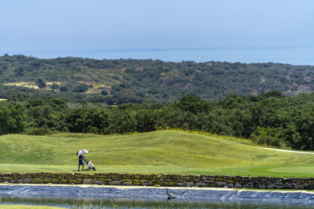 Person wheeling their bag across the fairway at San Roque Golf & Resort with trees in background